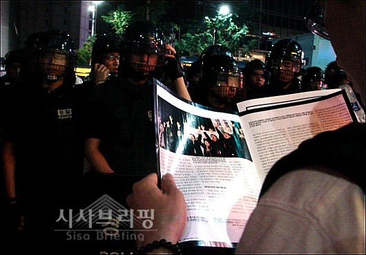 경찰과 대치 중 한 시민이 경찰을 앞에두고 책을 보고 있다.